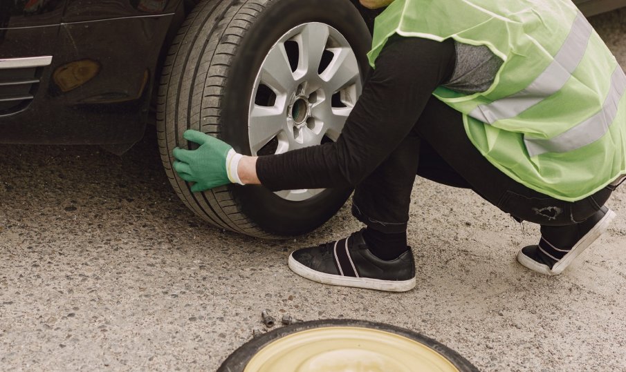 Кола премаза крака на мъж, докато сменял гума